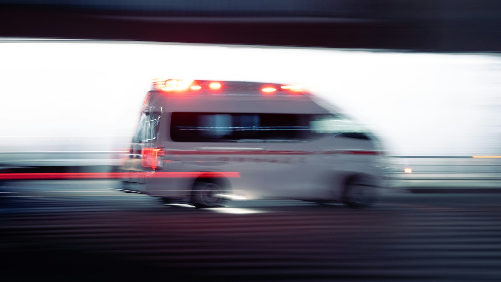 赤い警光灯をつけて夜の道路を走る日本の救急車